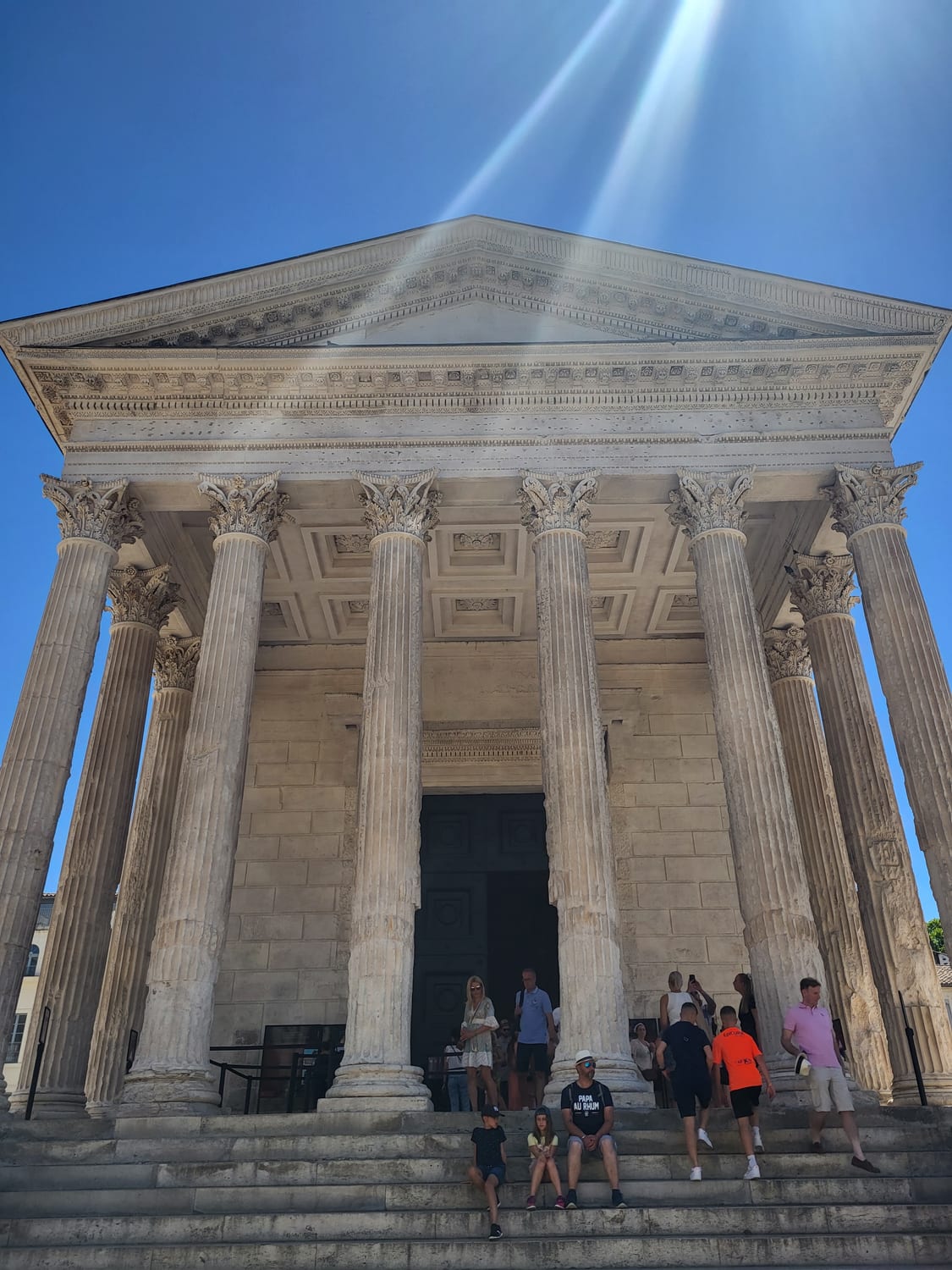 le colonne corinzie e il frontone della Maison Carrée di Nîmes visti dal basso, dalla scalinata