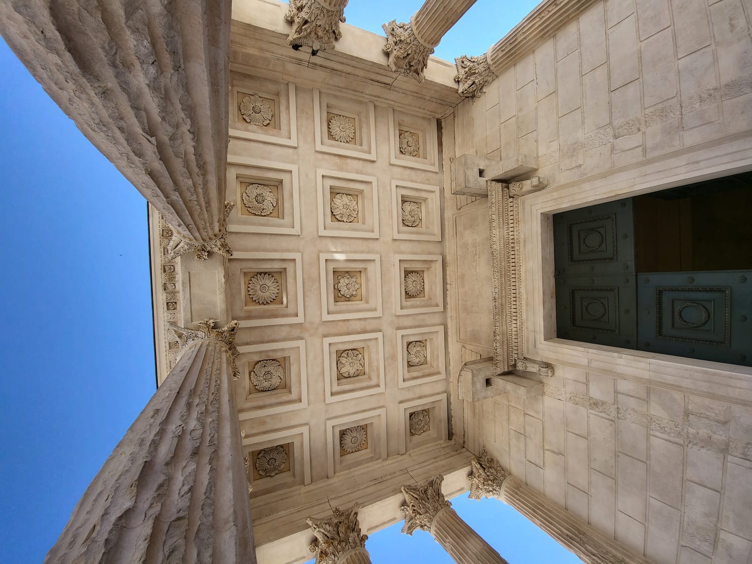 il soffitto a cassettoni del portico della Maison Carrée di Nîmes, con i rosoni scolpiti, visto dal basso