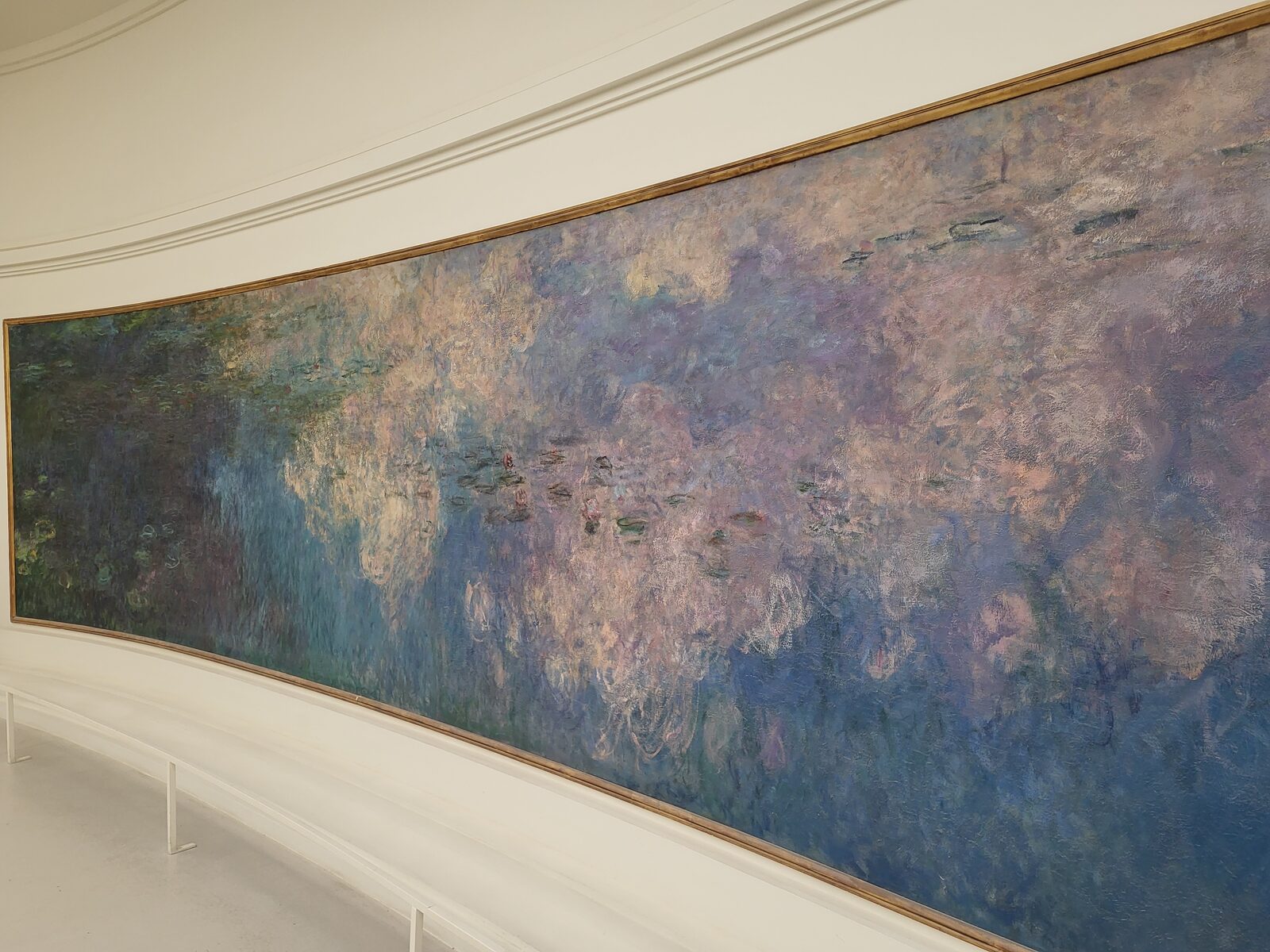 un panel de los Nenúfares de Monet en la sala oval del Musée de l’Orangerie, con la pared curva y la luz natural que entra desde arriba