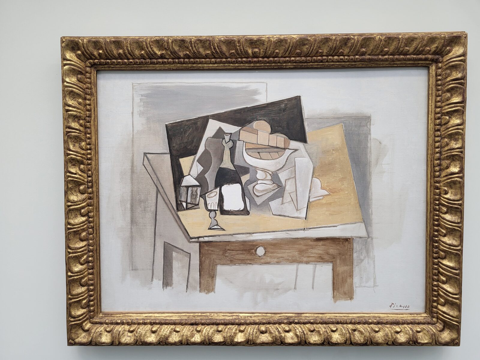 una natura morta cubista di Picasso con bottiglia, bicchiere e fruttiera scomposti su un tavolo