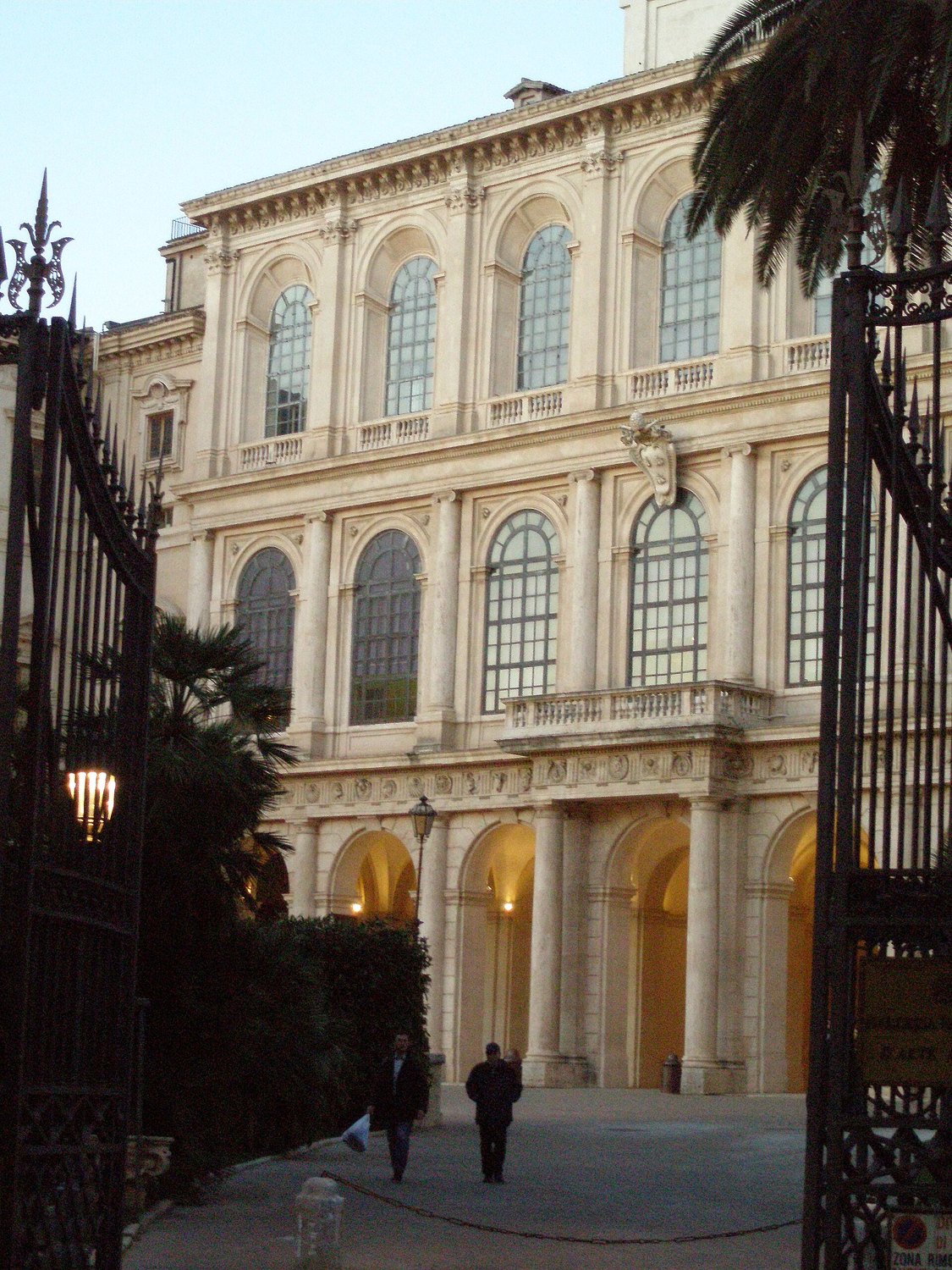 la fachada del Palazzo Barberini de Roma vista desde la verja, con el escudo de las abejas barberinianas y el pórtico iluminado