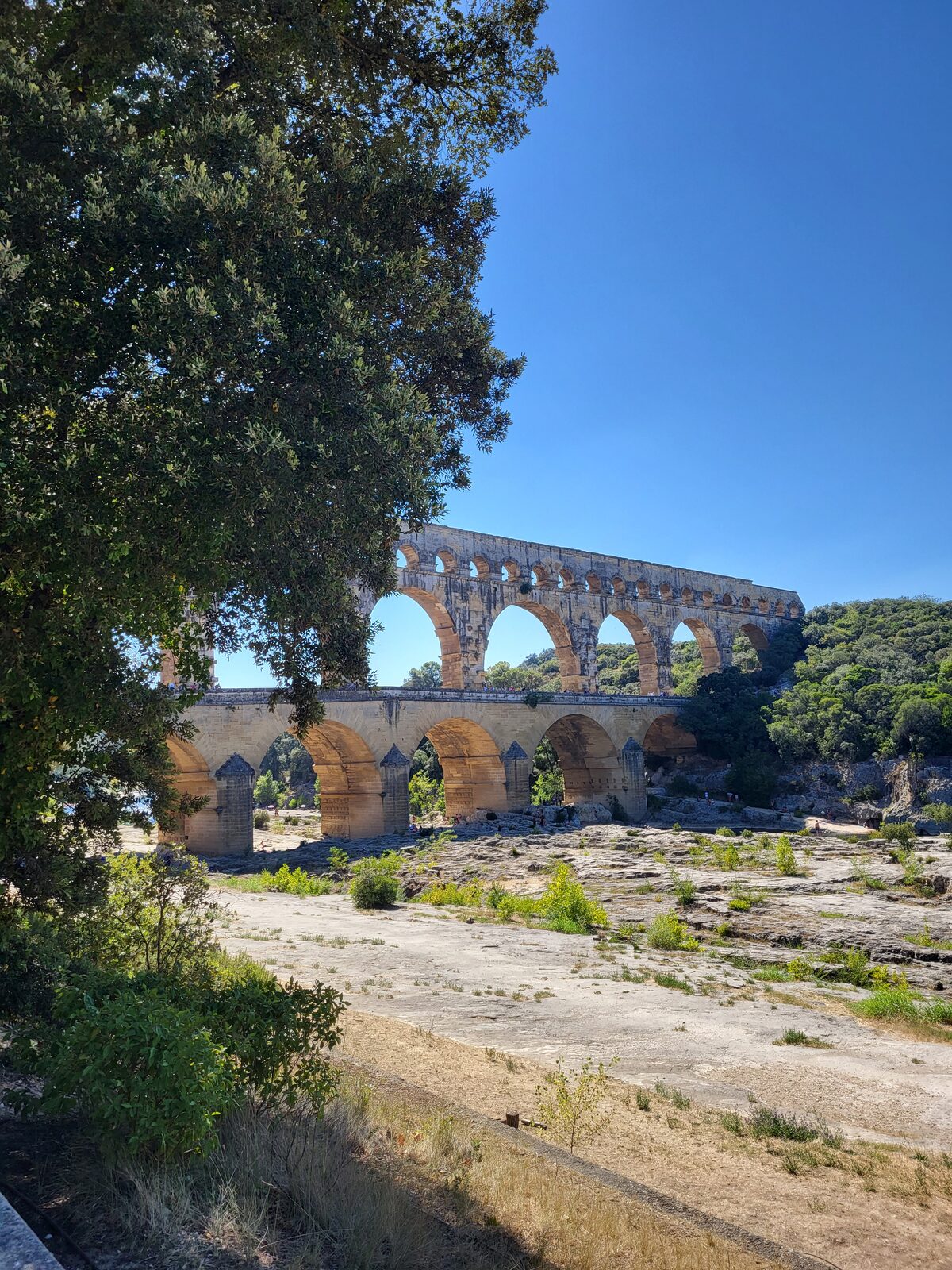 el Pont du Gard visto desde aguas abajo, con sus tres órdenes de arcadas y el lecho seco del Gardon en primer plano